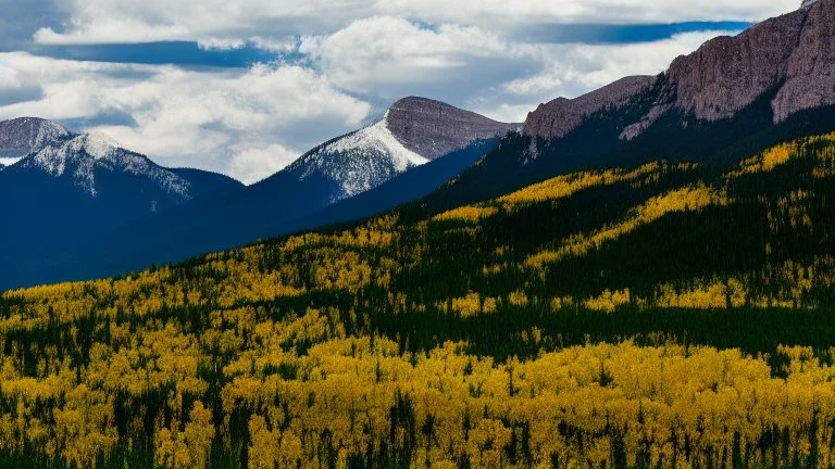 snow peaked rocky mountains with green plain below