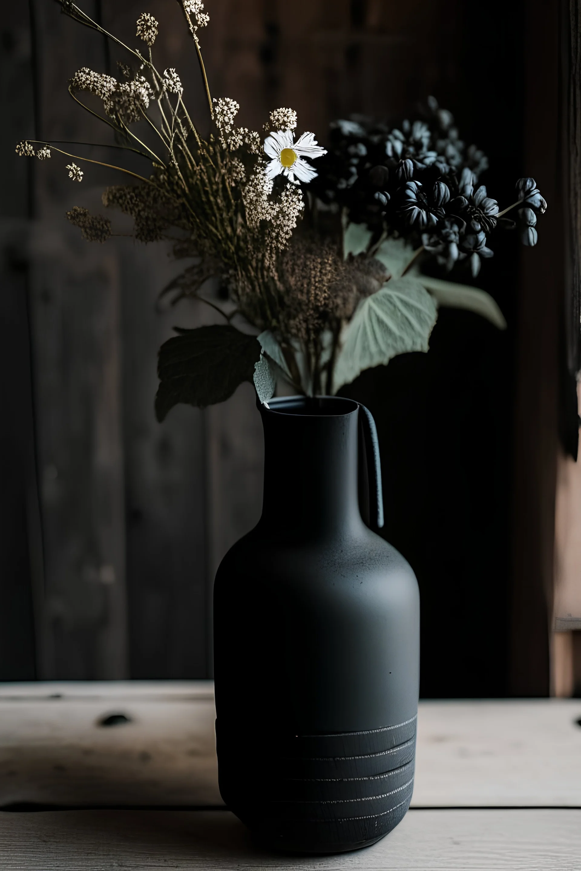 detail image of an old black ceramic vase with flowers on a wooden table. modern farmhouse style with rustic feeling.