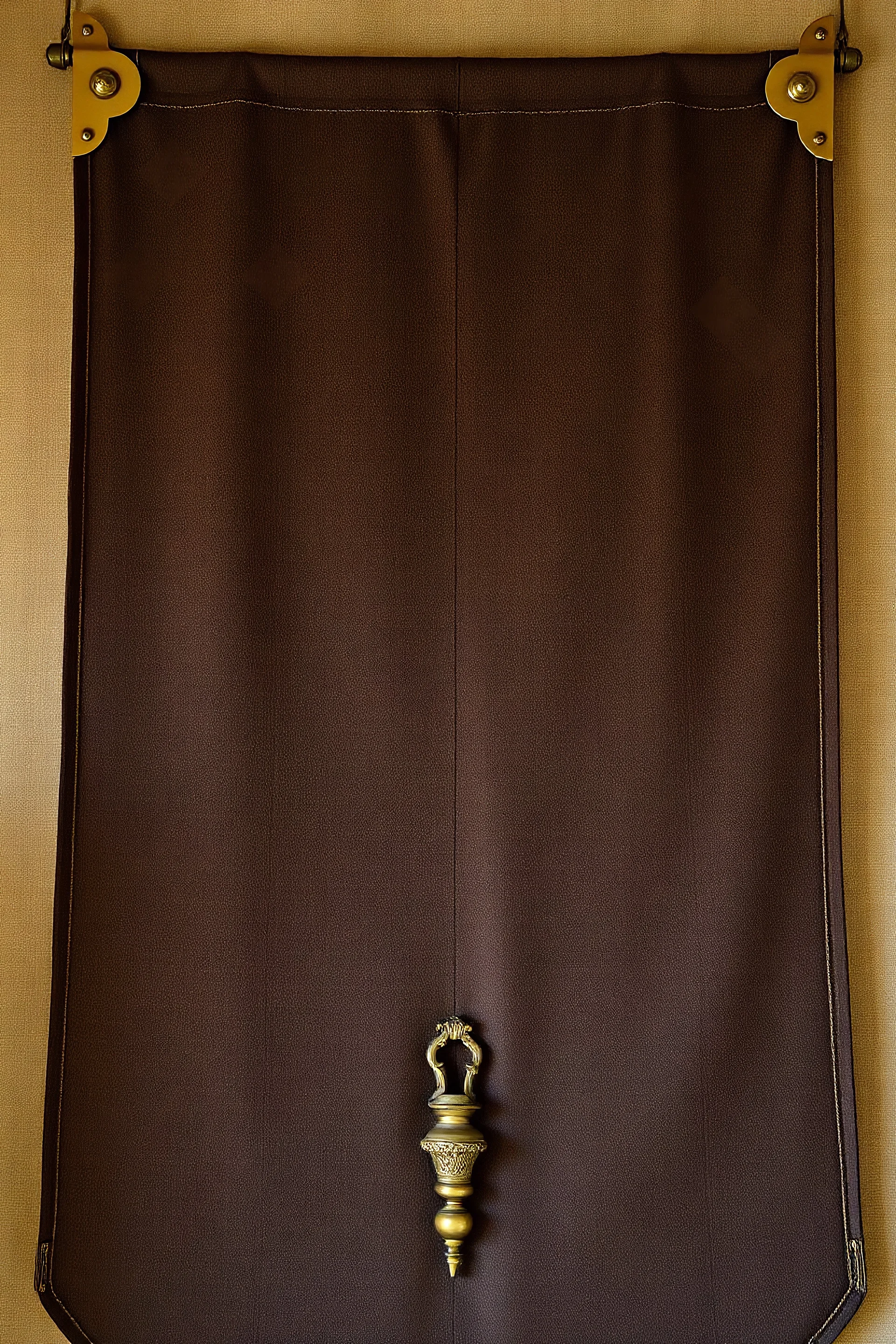 darker textured hanging fabric background, with decorative brass corners at top, and a heavy brass decorative element attach along the bottom