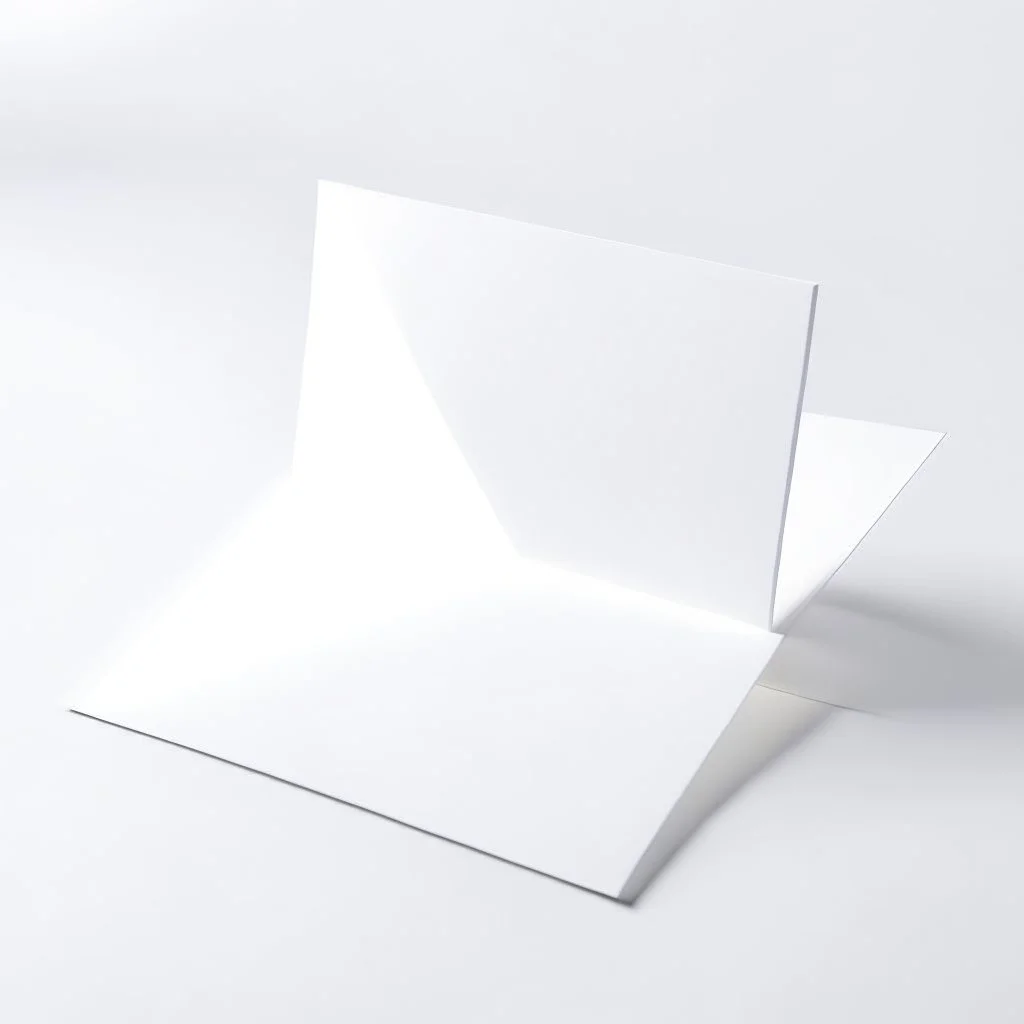 A photo of a white folded card, 5.5 by 4.25 inches. The card is laying vertically on a beautiful white surface.