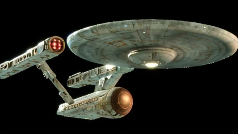 a screen capture from a star trek movie of a battle-damaged starship enterprise IN the year 2380 IS IN A BATTLE with monster ufos sci-fi meticulous, highly-polished, photorealistic, studio production, intricately detailed, GALACTIC, directed by gene Roddenberry, move saucer section forward and nacelles back