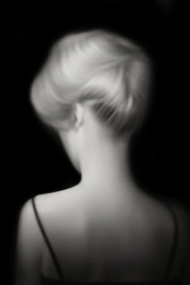 Mujer rubia de espaldas, retrato huge primer plano., iluminada potentemente desde atrás, Imagen en blanco y negro vaporoso, al estilo de la foto del fotógrafo Hugo Alonso.