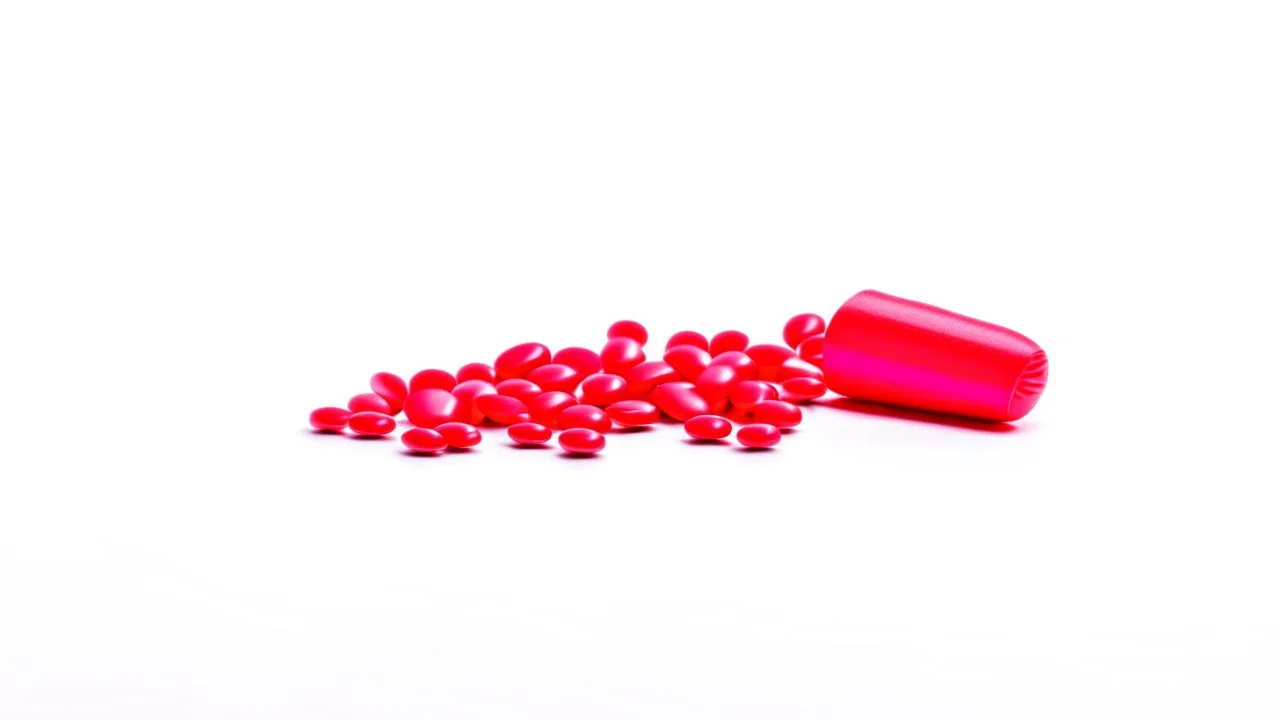 a bubble pack of red pills, a torn red ribbon, on a white background