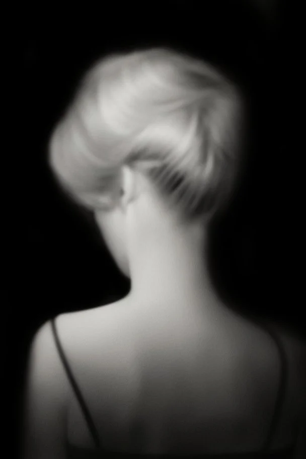 Mujer rubia de espaldas, retrato huge primer plano., iluminada potentemente desde atrás, Imagen en blanco y negro vaporoso, al estilo de la foto del fotógrafo Hugo Alonso.