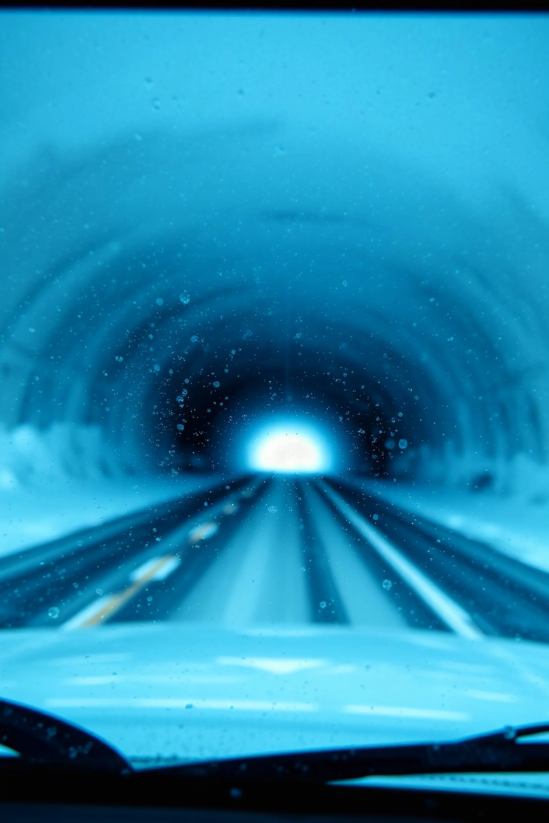 surreal tunnel road seen through a dirty truck front window, dirty blue snow and wind
