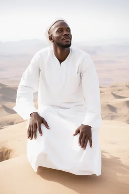 african man wearing white thobe. standing on high mountain looking out to the desert