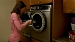 very confused young woman places a few metal spoons into her household dryer