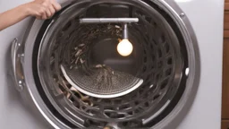 very confused young woman puts a fewmetal spoons inside the household dryer