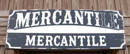 fill composition with large and wide hand painted old western sign that reads: "MERCANTILE" white on black with inset white stripe boarder aged paint on wood sanserif