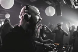 en manlig skallig och goatee (ansat skägg) DJ (med hörlurar) som sjunger nära in i kameran, väldigt exalterad, och folk som dansar våldsamt i backgrunden på ett techno disco, svartvit bild, prodigy trash style