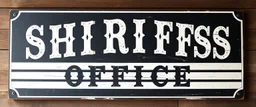 fill composition with large and wide historical hand painted old western sign that reads: "SHRIFFS OFFICE" white on black with inset white stripe boarder aged paint on wood sanserif