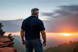 a brawny man with grey hair views sunset from a cliff