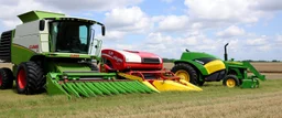 Parked at the edge of a field is a Claas brand Combine(left)seeder(middle) and a John Deere Tractor with seeder(right) simplified