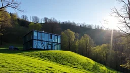 Contemporary glass and steel house nestled in a lush, green valley during a sunny spring afternoon, reflecting the surrounding trees and sky.