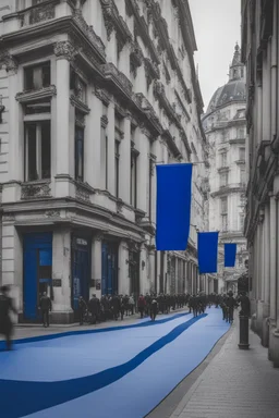 A full street in a big city with frech style building. The street is filled with blue flags