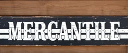 fill composition with large and wide hand painted old western sign that reads: "MERCANTILE" white on black with inset white stripe boarder aged paint on wood sanserif