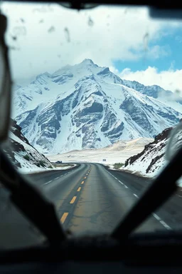 surreal mountain road seen through a dirty truck front window, dirty yellow snow and wind