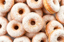 background filled with fresh old-fashioned mini doughnuts completely covered in powdered sugar