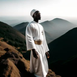 African man in white thobe, standing on top of mountain