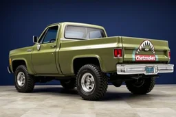 side of 1976 Chevrolet square body truck(military green), with shark nose graphic behind front wheel, navy blue background