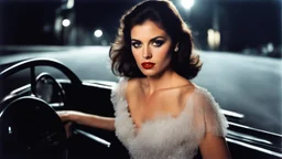 [artistic photo by Tony Kent (1980)] a brunette driving a car bends over to speak, she looks at the camera, she is going to a party, she is mysterious and her dress does not conceil much, the street is dark