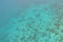 Aerial view of desert island in blue glossy sea, no trees, no plants, no green