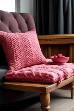 image of a wooden table with a pink, knitted pillow
