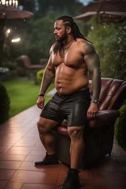 half figure shot photography of a burly heavyset gipsy shirtless man, 28 years old in bulging shorts, tattoo, manly chest, short dreadlocks , sweat, wet, relaxing on a chair, in a private elegant garden of a villa, raining nighttime, big shoulders, big tights, ambient occlusion, photorealistic, frontal view from the ground, dim light from little bulbs