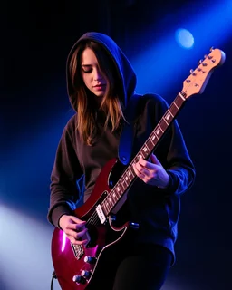 attractive woman(wearing a dark hoodie of light material) playing an electric guitar at vertical angle