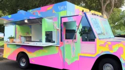 modern looking food truck that has a bunch of bright paint and flashy lights