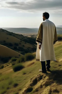 A person in Andalusian clothing standing on a hill with his back