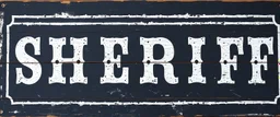 fill composition with large and wide historical hand painted old western sign that reads: "SHERIFF" white on black with inset white stripe boarder aged paint on wood sanserif