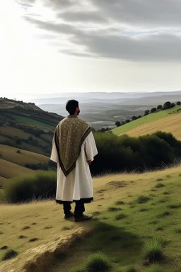 A person in Andalusian clothing standing on a hill with his back