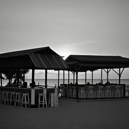 Terraza de un chiringuito frente a la playa al atardecer, fotografía realizada con una cámara Leica y con un objetivo de 50 mm, fotografía real, fotografía en blanco y negro