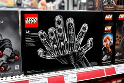 Lego box on display at a toy store shelf, LEGO™️ box labeled "BEKSINSKI", image on box is a nihilistic six fingered hand made out of Lego blocks with nightmarish faces on the fingertips, sinister, pronounced clear LEGO block raised pip textures on all surfaces, unsettling juxtaposition of lego fun and Zdzislaw Beksinski's nightmare surreal art