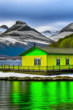 donkergeel noors houten huisje bij fjord met blauwgroen water en berg met sneeuw in de verte op de achtergrond. Het huisje is klein en je ziet veel omgeving