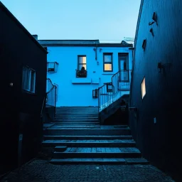 Fotografia di strada assurda e falsa orripilante blu weirdcore dai colori vivaci, liminalcore. Escher. Scale che scendono. Yves Tanguy. Non luogo falso, inusuale. Le case sono false e dipinte di nero chiaro con cose stilizzate e dettagli. Ci sono finestrelle false quadrate, che danno un senso distopico e molto surreale, disposte in modo casuale. L'atmosfera generale sembra noiosa e onirica, con un contrasto tra elementi reali ed elementi dipinti falsi, René Magritte, oddest things