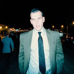 very grainy discolored photo, portrait, night street, grunge, 2000s Russia, businessman, extremely gaunt, haughty, nice suit, extremely pale, inhuman