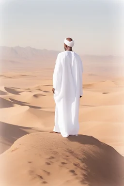 african man wearing white thobe. standing on high mountain looking out to the desert