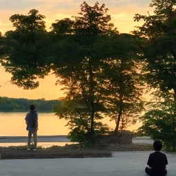 In the anime, a young male character is near the green lake in the sunset afternoon.