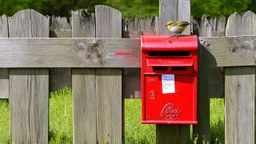 an old wooden fence with a little bird on it, a red old mailbox on the fence, a big note stuck on the mailbox