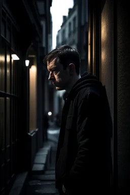 man in dark clothing, hiding around a corner., looking out on a brightly lit street