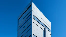 Capture a minimalist image of a modern building against a clear and cloudless sky. Try to focus on sharp geometric lines and contrasting light and shadow.