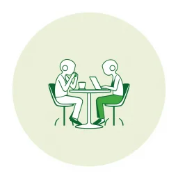 A circular logo in a distinctive green color, with two people sitting around a two-person table with their heads shaped like coffee cups, one drinking coffee and the other working on their laptop.