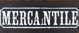 fill composition with large and wide historical hand painted old western sign that reads: "MERCANTILE" white on black with inset white stripe boarder aged paint on wood sanserif