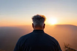 a brawny man with grey hair views sunset from a cliff