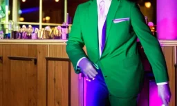 man in a green suit in a restaurant with purple lights, dancing on a pole