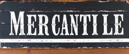 fill composition with large and wide hand painted old western sign that reads: "MERCANTILE" white on black with inset white stripe boarder aged paint on wood sanserif