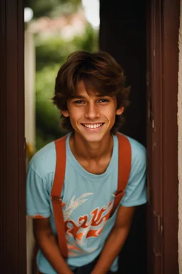 15 year old young boy with lightly tanned skin and medium length brown hair wearing a teeshirt, standing by a door, smiling