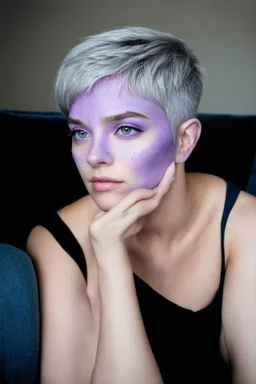 A young woman with lavender skin, purple eyes, silver hair in a pixie cut with purple freckles sits in an armchair looking thoughtful.